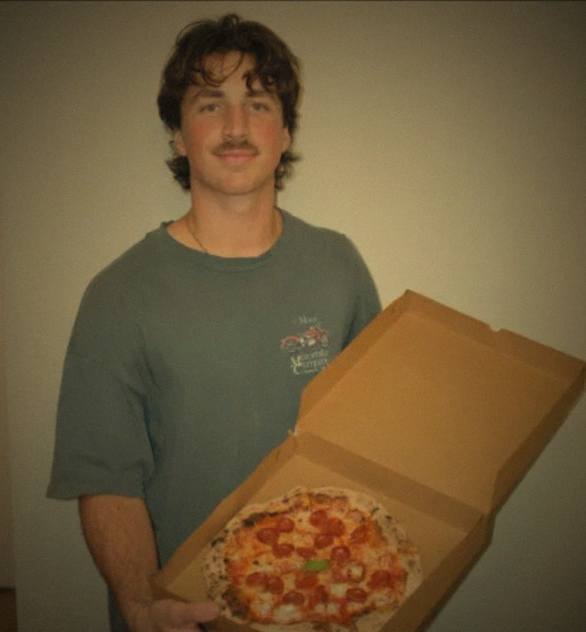 Malachi Blackington holding a fresh pizza in an open box